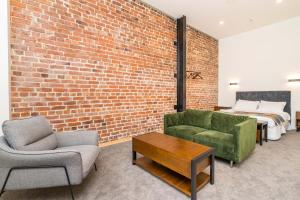 - une chambre avec un mur en briques, un lit et un canapé dans l'établissement Princes St Apartments, à Dunedin