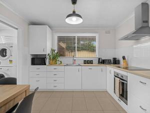 a white kitchen with white cabinets and a table at Nook on Nixon in Shepparton
