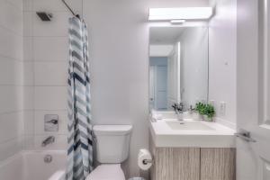 a white bathroom with a toilet and a sink at RivetStays - The Jarvis in Toronto
