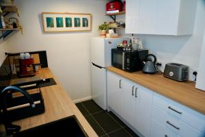 a kitchen with white cabinets and a white refrigerator at 3 Waters Guest Accommodation in Gold Coast