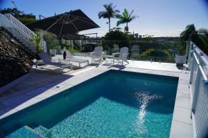 a swimming pool with chairs and an umbrella on a house at 3 Waters Guest Accommodation in Gold Coast