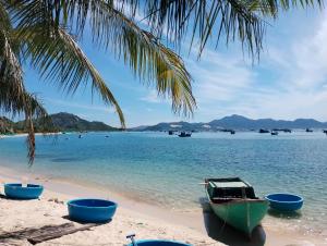 a beach with two boats and a palm tree at The Sunrise Anh Tu in Cam Ranh