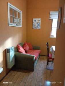 ein Wohnzimmer mit einer grünen Couch mit roten Kissen in der Unterkunft Alojamiento jv CABAÑA in Nogales