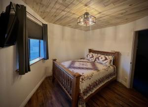 a bedroom with a bed and a window and a chandelier at THE SNUGGLE INN in Loa