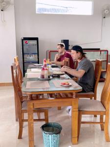 dos hombres sentados en una mesa en un restaurante en Queens Backpackers Hostel, en Vang Vieng