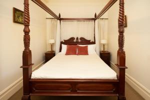 a bedroom with a four poster bed with red pillows at Leura House in Leura