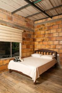 ein Schlafzimmer mit einem Bett in einer Ziegelwand in der Unterkunft Posada Campestre Ecoturística Granja Julieth in San José del Guaviare