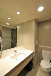 a bathroom with a sink and a toilet and a mirror at Garden Orchid Hotel & Resort Corp. in Zamboanga