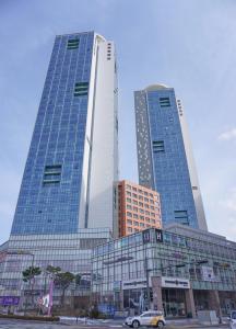 two tall buildings in a city with a car in front at Dahlbit stay in Incheon