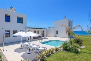 Villa con piscina con sillas y sombrillas. en Villa Panaxia Akte, en Theologos