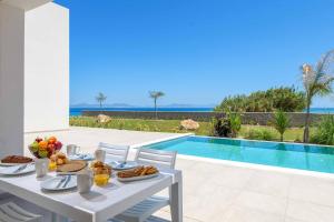 una mesa blanca con comida junto a una piscina en Villa Panaxia Akte, en Theologos