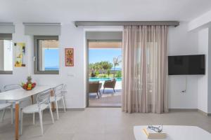Una sala de estar con una mesa de comedor y un televisor. en Villa Panaxia Akte, en Theologos