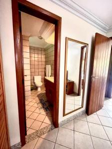 een badkamer met een toilet en een spiegel bij Apartamento Sogno D' Estate in Porto Seguro