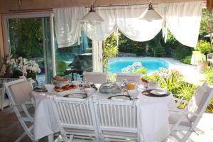 uma mesa branca com comida em frente a uma piscina em Lou Pero Mousco em Saint-Paul-en-Forêt