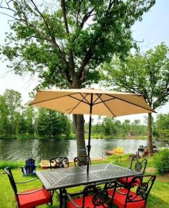 a table with an umbrella in front of a lake at On The Rocks A Waterfront Cottage on Stoney Lake in woodview