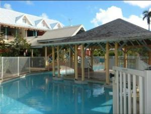 einen Pool mit Pavillon neben einem Haus in der Unterkunft Studio avec piscine partagee jardin clos et wifi a Sainte Anne a 1 km de la plage in Sainte-Anne