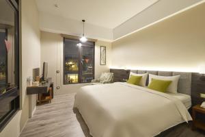 Un dormitorio con una gran cama blanca y una ventana en Hotel Z, en Taichung