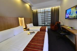 ein Hotelzimmer mit 2 Betten, einem Schreibtisch und einem TV in der Unterkunft Hotel Grand Central in Singapur