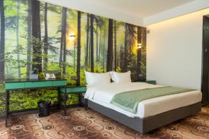 1 dormitorio con 1 cama y un mural forestal en MB Hotel, 