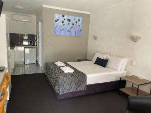 a hotel room with a bed and a kitchen at Bundaberg Spanish Motor Inn in Bundaberg