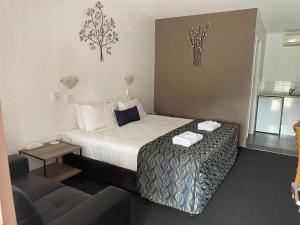 Habitación de hotel con cama y sofá en Bundaberg Spanish Motor Inn, en Bundaberg