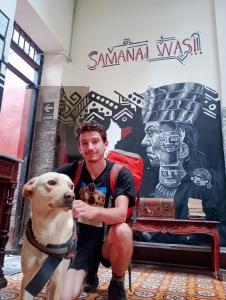 Un uomo con un cane davanti a un negozio di Samanai Wasi Hostel a Lima