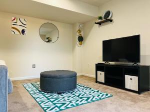 a living room with a television and a blue ottoman at The CozeeNest in Hagerstown