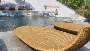 2 sillas de mimbre sentadas junto a una piscina en The Bluestone Lodge en Ha Giang