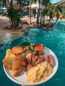 een bord eten op een tafel naast een zwembad bij Mercure Darwin Airport Resort in Darwin