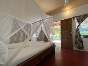 ein Schlafzimmer mit einem Himmelbett und einem Fenster in der Unterkunft Afro Rooms & Tents in The Beach in Kilindoni