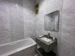بوتيك هاوس بدخول ذاتي وصالة أنيقة في حائل: حمام مع حوض أبيض ومغسلة وحوض استحمام