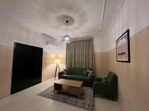 ein Wohnzimmer mit einem grünen Sofa und einem Tisch in der Unterkunft بوتيك هاوس بدخول ذاتي وصالة أنيقة in Ha'il