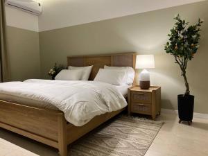 a bedroom with a large bed with a lamp and a plant at بوتيك هاوس بدخول ذاتي وصالة أنيقة in Hail