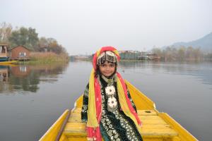 Une jeune fille assise dans un bateau sur l'eau dans l'établissement Double tree irshad, à Srinagar