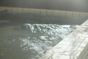 uma banheira cheia de água ao lado de uma parede em Frame Hotel Sapporo em Sapporo