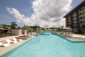 a swimming pool with chairs and a hotel at Ibis Darwin Airport Hotel in Darwin