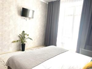 um quarto com uma cama e uma televisão na parede em Комфортные апартаменты на ЭКСО em Prigorodnyy