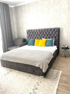 um quarto com uma cama grande com almofadas amarelas e azuis em Комфортные апартаменты на ЭКСО em Prigorodnyy
