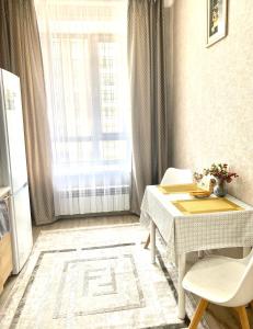 uma sala de jantar com uma mesa e uma janela em Комфортные апартаменты на ЭКСО em Prigorodnyy