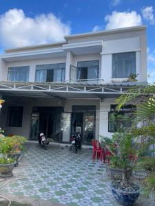 une maison blanche avec des motos garées devant dans l'établissement Biệt Thự Nghỉ Dưỡng Đảo Phú Quý, à Cu Lao Thu