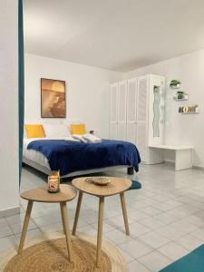 1 dormitorio con 1 cama con manta azul y 2 mesas en La Kawanaise Blue Lagon, en Grand-Bourg