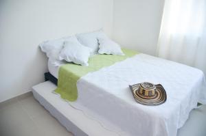 een bed met een witte deken met een kam erop bij Reserva de la sierra in Gaira
