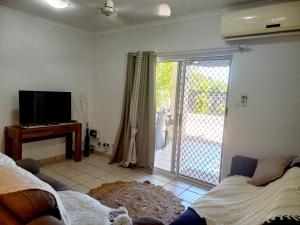 a living room with a bed and a sliding glass door at Sunset Stay in Darwin