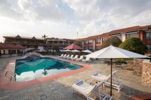 a pool at a hotel with chairs and umbrellas at Hotel Pokhara Grande in Pokhara