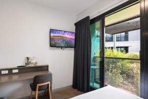 um quarto com uma televisão, uma secretária e uma janela em Ibis Darwin Airport Hotel em Darwin