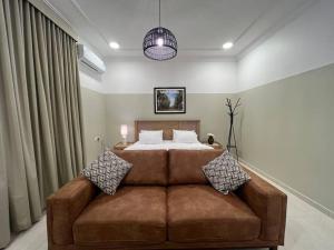 1 dormitorio con cama y sofá marrón en بوتيك هاوس بغرفة نوم أنيقة en Sidīs