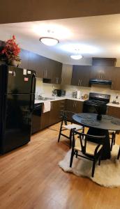 a kitchen with a table and a black refrigerator at Daisy home- one bedroom apartment in Lloydminster