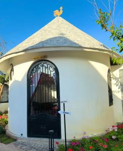 eine kleine Kapelle mit einer schwarzen Tür mit einem Hund oben in der Unterkunft Trulli Villa Homestay Đà Lạt in Phú Thạnh