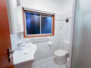 ein Badezimmer mit Toilette und Waschbecken und einem Fenster in der Unterkunft Collingwood Beach Cottage - Belle Escapes Jervis Bay in Vincentia + 17 Fotos