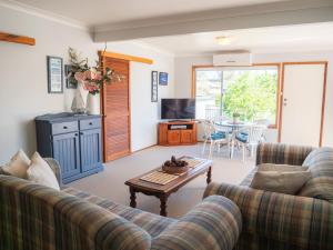 Sala de estar con 2 sofás y mesa en Collingwood Beach Cottage - Belle Escapes Jervis Bay, en Vincentia